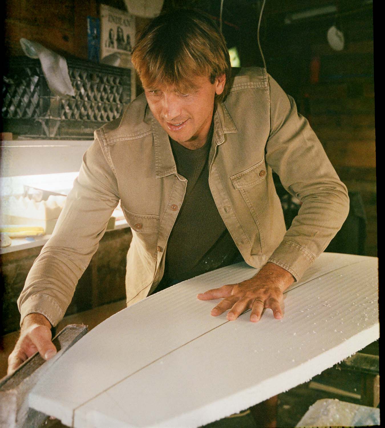 Man working on a surfboard in a workshop setting