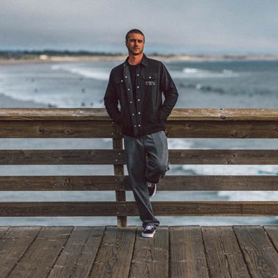 Man leaning on a wooden railing by the ocean