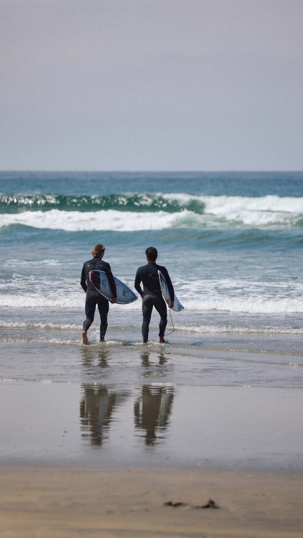 Two surfers walking out into the water
