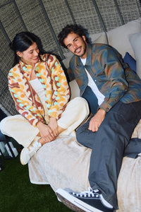 Two people sitting on a couch with a textured wall and green floor in the background