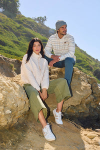 Two people sitting on rocks with a scenic background