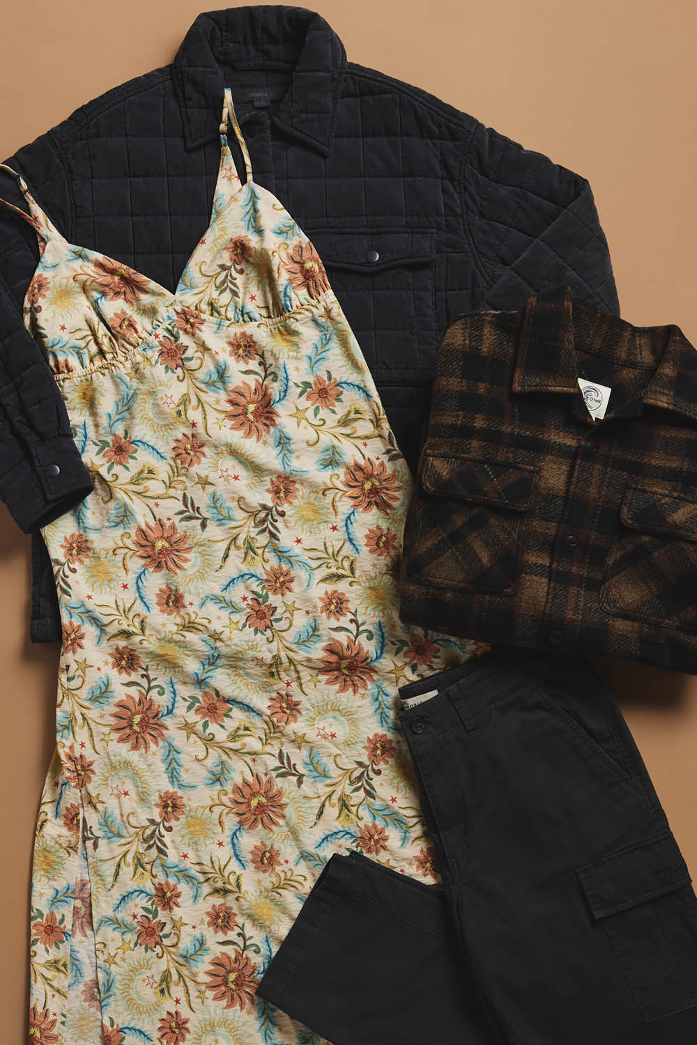 Collection of clothing items including a floral dress, quilted jacket, plaid shirt, and black pants on a beige background.