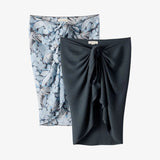 Two skirts, one floral and one solid black, on a white background