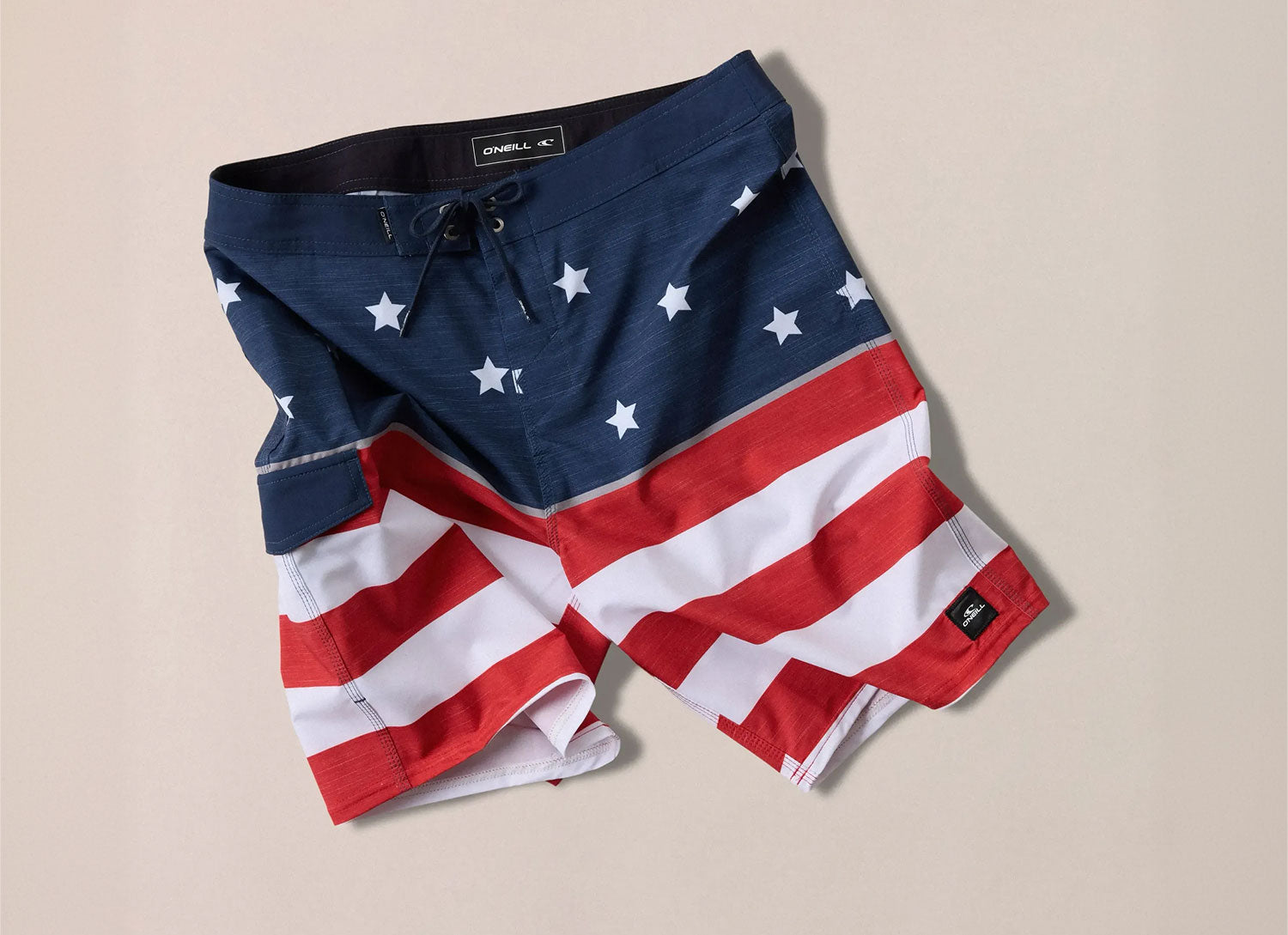 American flag patterned boardshorts on a beige background